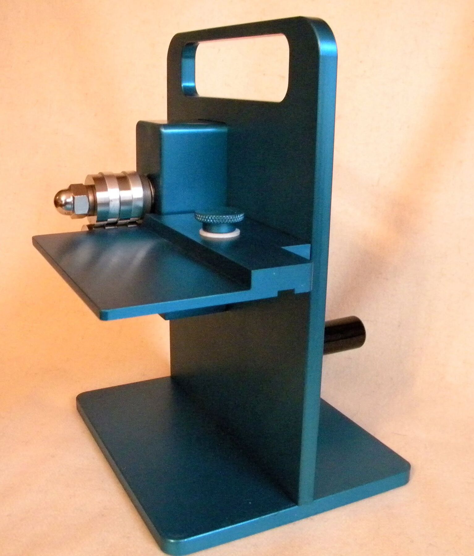 A blue anodized Honeydoo fabric strip cutter with its feed tray extended, shown against a warm tan backdrop A blue anodized Honeydoo fabric strip cutter with its feed tray extended, shown against a warm tan backdrop